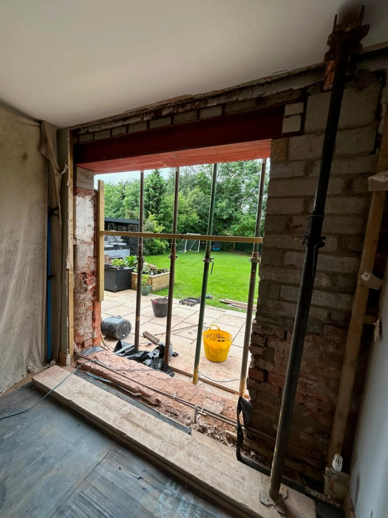 Steel RSJ beam installed in a brick wall opening supported by vertical Acrow props during a home renovation.